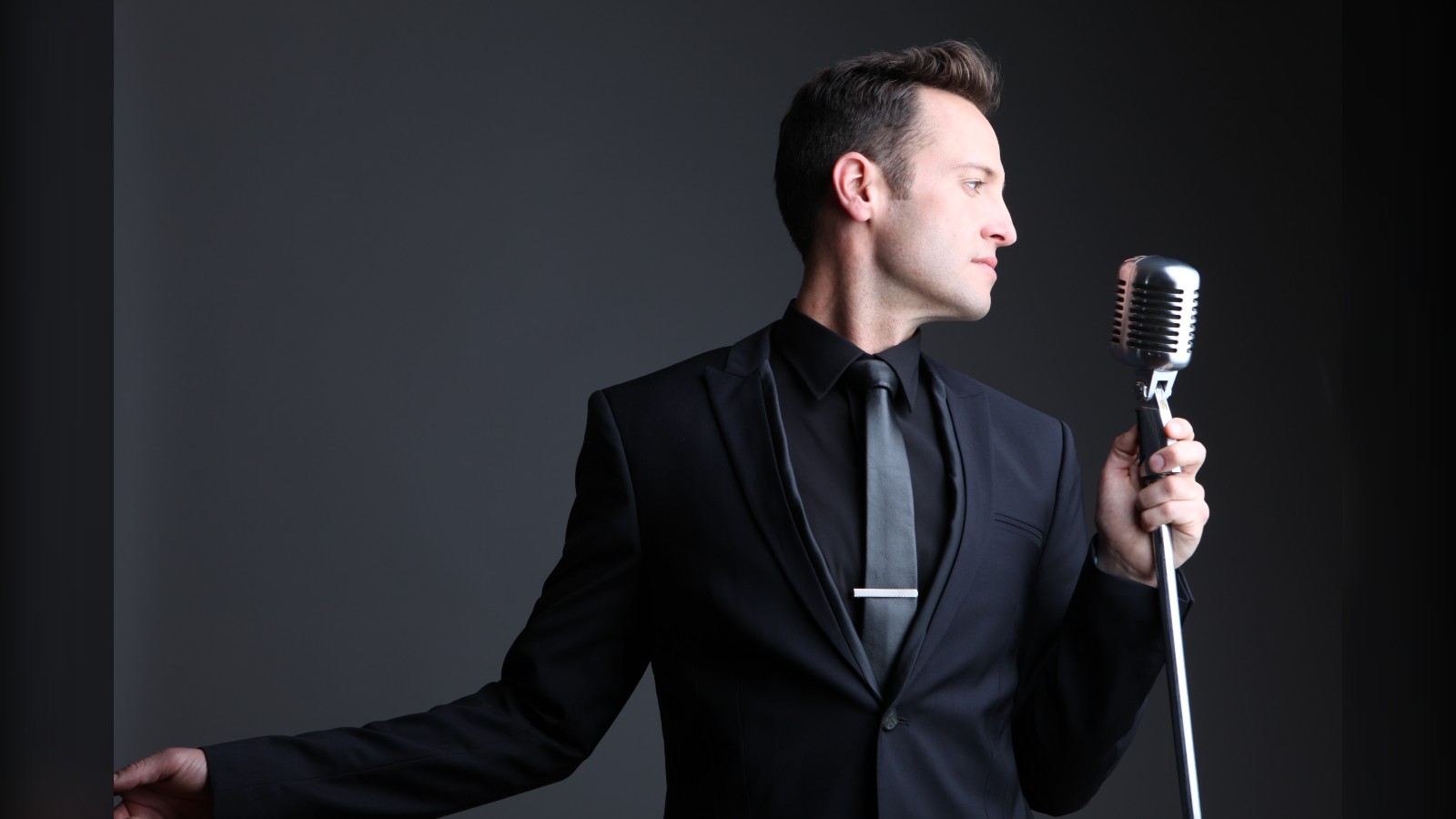 Branden James, tenor, in a black suit at a vintage microphone